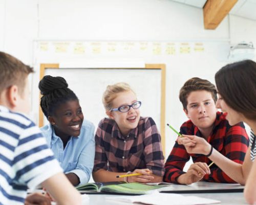Group Of Teenage Students Collaborating On Project In Classroom